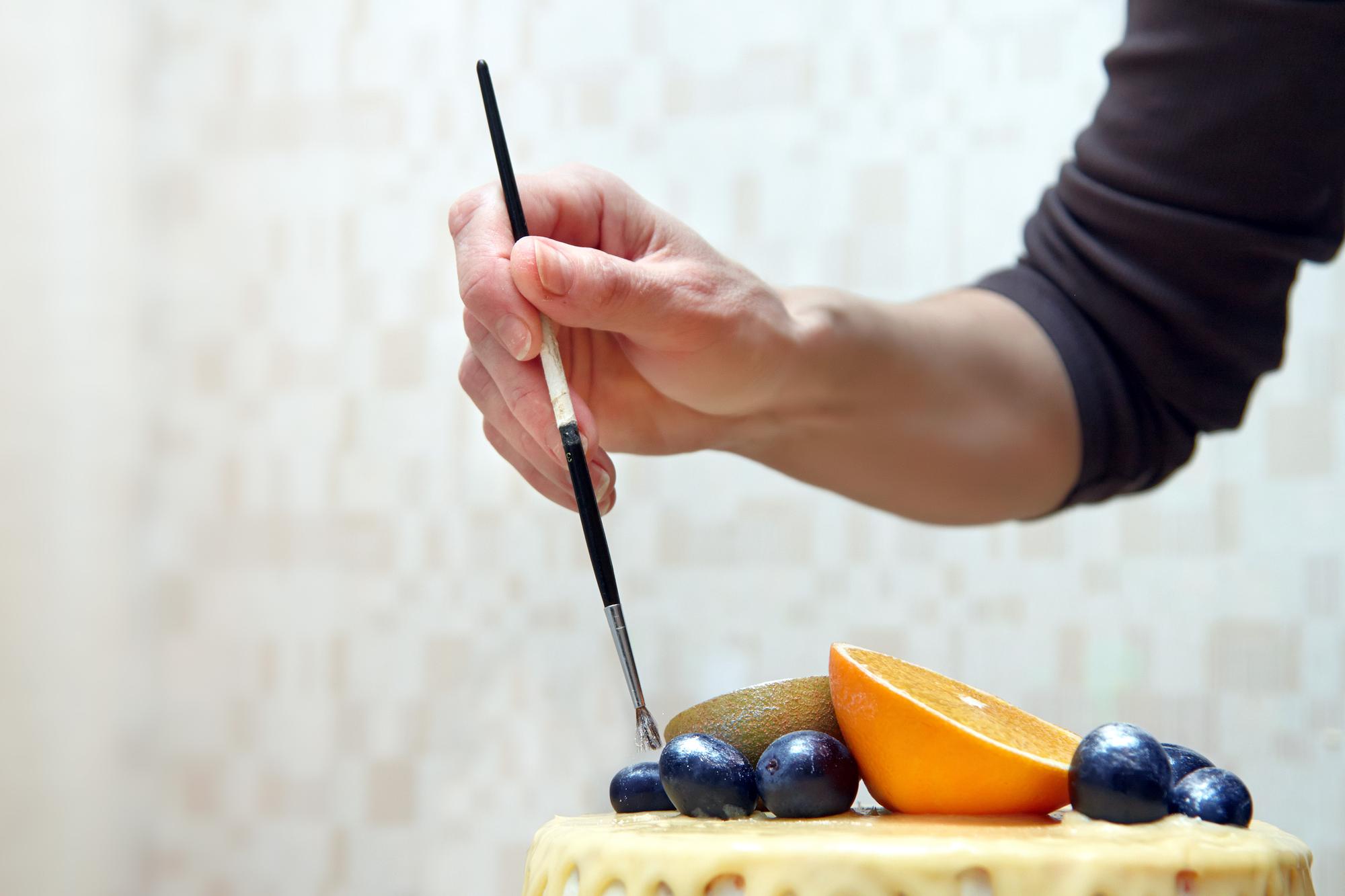 Close-up of hands garnishing a dessert